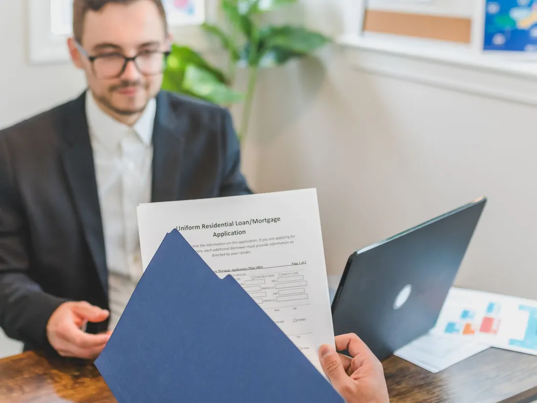 A loan officer reviewing a printed amortisation schedule with a client at a desk.